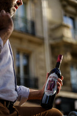 Person holding a bottle of Baldovin Vermouth in an urban setting