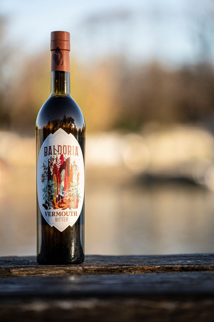 Bottle of Baldoria Vermouth Bitter on a wooden surface with a blurred natural background