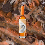 Bottle of Pinhook Kentucky Straight Bourbon Whiskey over backdrop of unidentifiable materials.