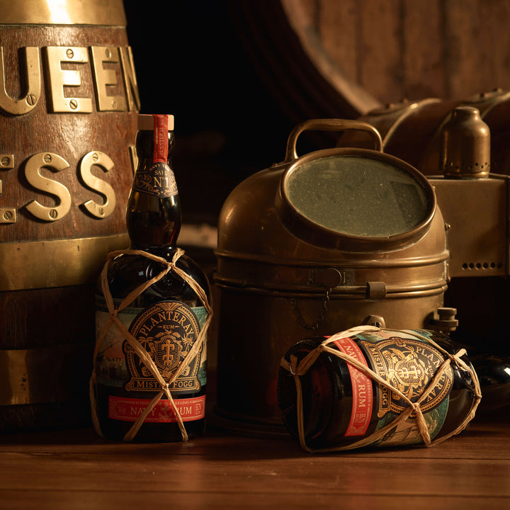 Two bottles of Planteray Mister Fogg Rum on a table next to some nautical items.