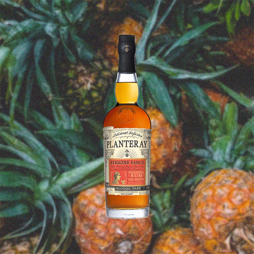 750ml bottle of Planteray Stiggins' Fancy Pineapple Rum - against a backdrop of fresh pineapples.