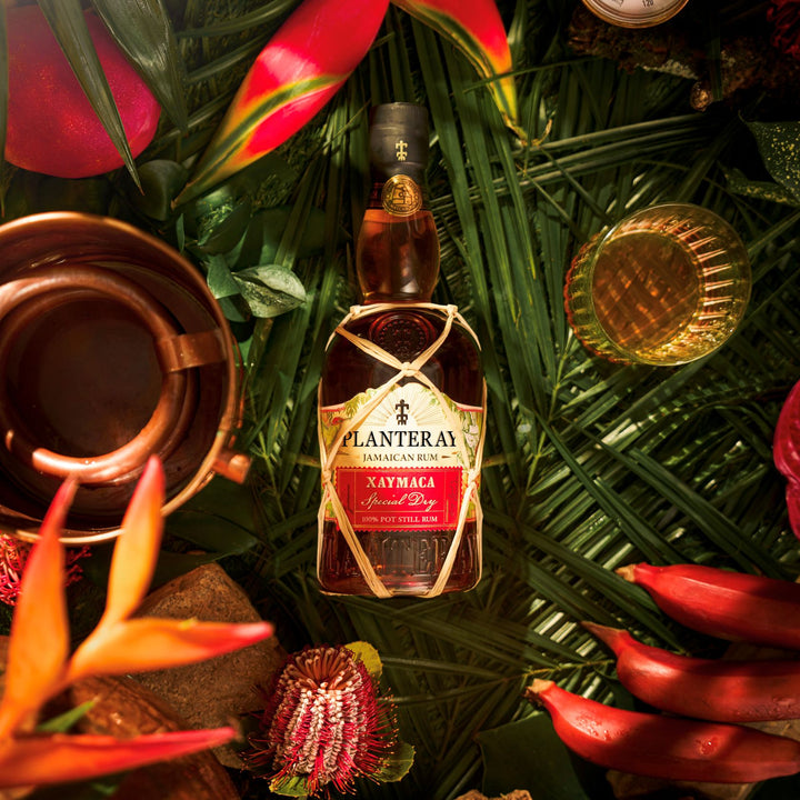 Bottle of Planters Jamaican Rum surrounded by tropical leaves and flowers