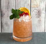 Cocktail with ice, lemon wedge, and garnish on a wooden surface