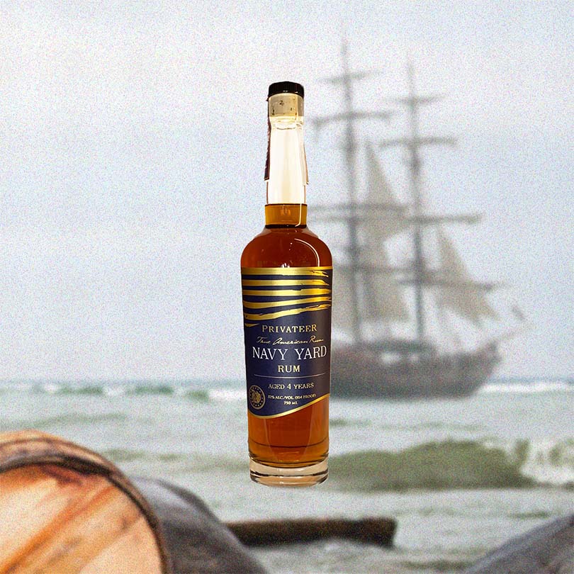 Bottle of Privateer Navy Yard 4 Year Aged Rum over backdrop image of a sail boat.