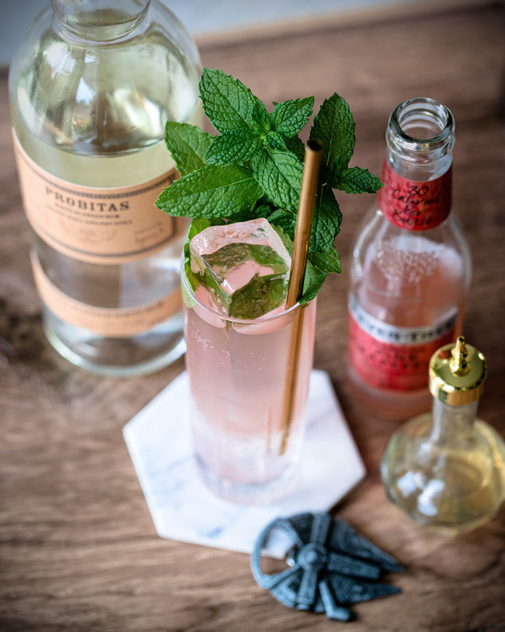 Cocktail with mint leaves and a Probitas bottle on a wooden surface