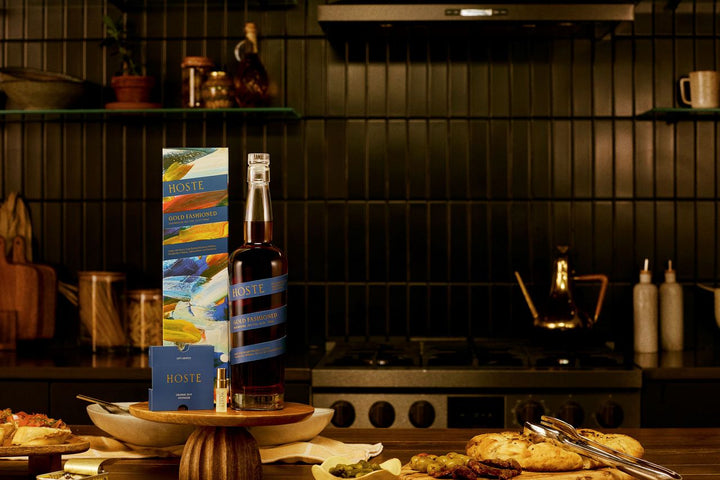 Bottle of wine and snacks on a kitchen counter with a dark tiled wall in the background.