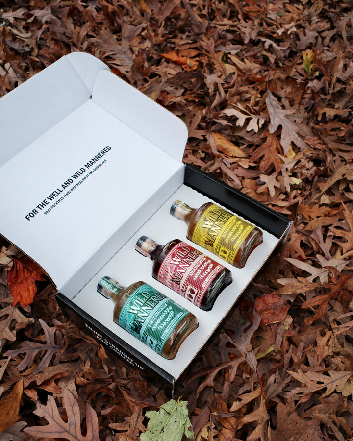 Set of miniature bottles in a box on a bed of autumn leaves