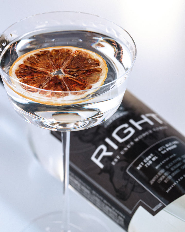 Cocktail glass with a dried orange slice and a bottle of Johnnie Walker Black Label whisky.