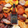 A bottle of amber colored liquid with The Real McCoy Single Blended Rum Aged 12 Years on the label.  Foursequare Distillery, St. Philip, Barbados, at the bottom.  All of this against a backdrop of appetizing looking dried fruits and nuts, evoking the taste of The Real McCoy 12 Year.