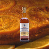 Bottle of Rhum Barbancourt 15 Year Estate Reserve Haitian Aged Rum over backdrop image of sliced fruit up close.