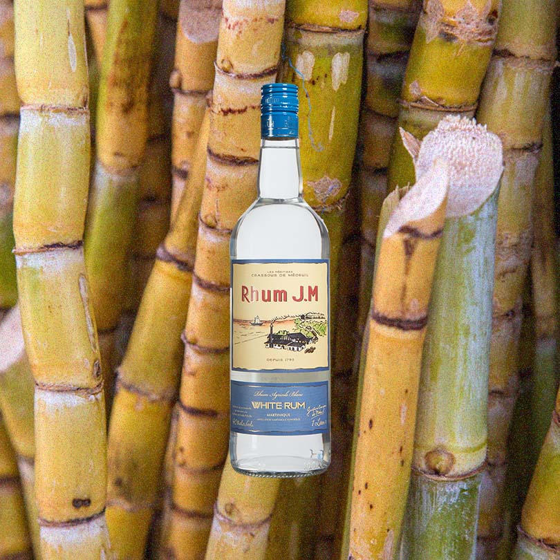 Bottle of Rhum J.M Agricole Blanc 80 White Rum over backdrop image of sugar cane.