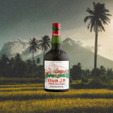 Bottle of Rhum J.M Terroir Volcanique Rum over backdrop image of a mountain and palm tree.