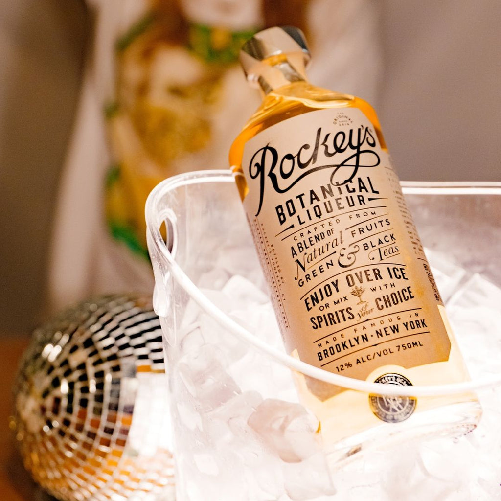 Bottle of Rockey’s Botanical Liqueur in a bucket of ice on a table.