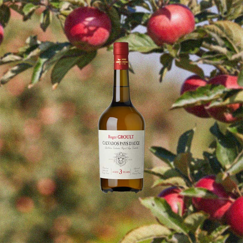 Bottle of Roger Groult 3 Year Reserve Pays D'Auge Calvados over backdrop image of an apple tree.