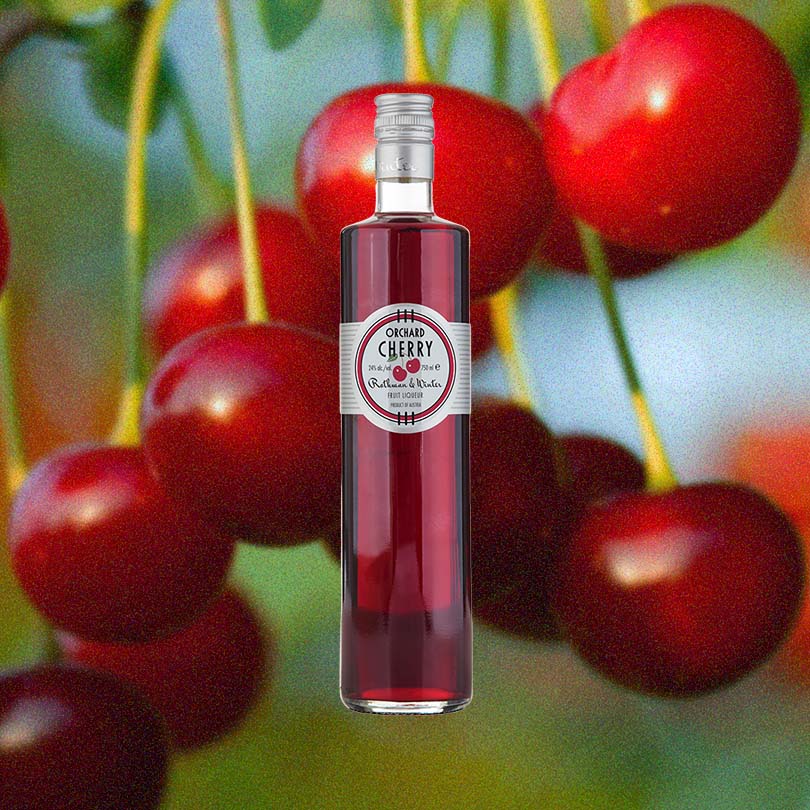 A bottle of Orchard Cherry Liqueur from Rothman & Winter, set against a backdrop of sour cherries hanging from a cherry tree.