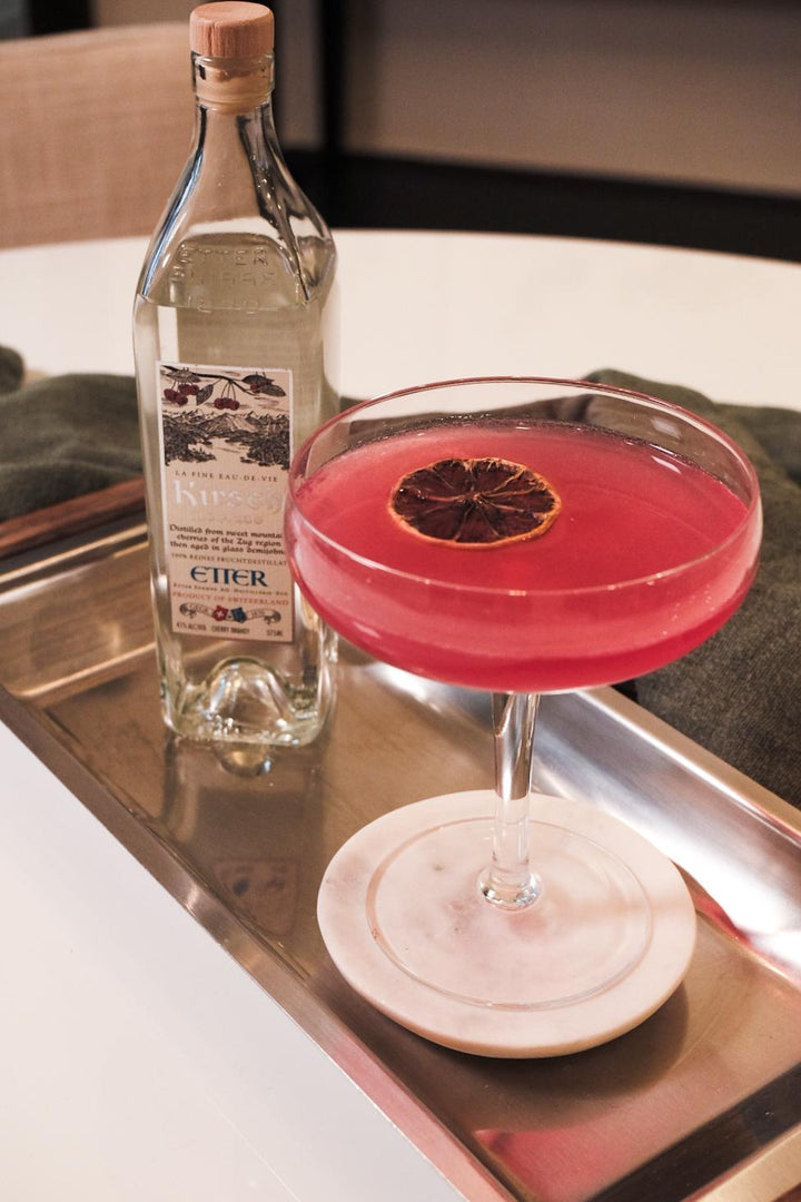 Cocktail with a red rim and bottle of Etier on a tray