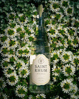 Bottle of Saint Rhum laying flat on a bed of flowers.