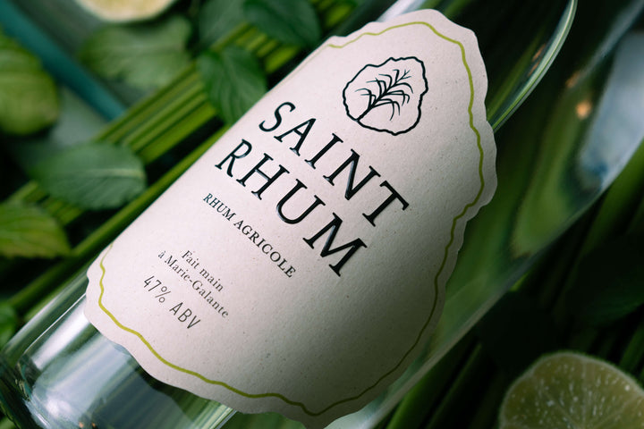 Up close of the label on a bottle of Saint Rhum Rum. In the background is are green leaves.