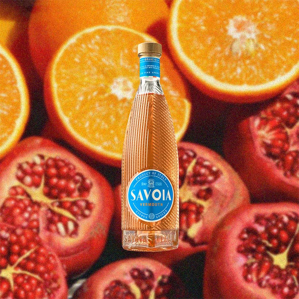 Bottle of Savoia Orancio over backdrop image of sliced orange and pomegranate. 