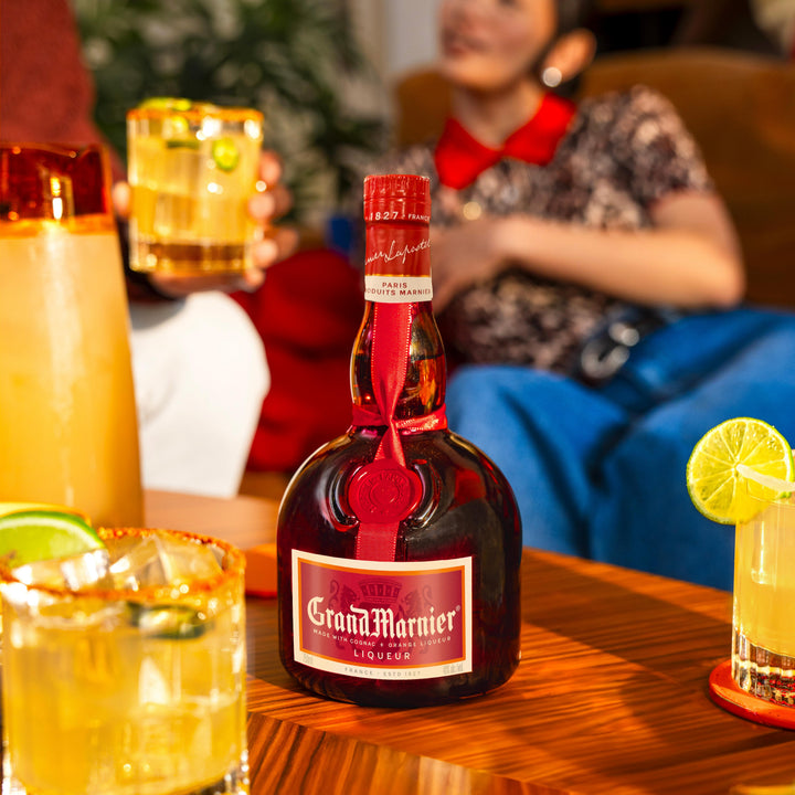 Bottle of Grand Marnier with cocktails on a table, blurred person in the background