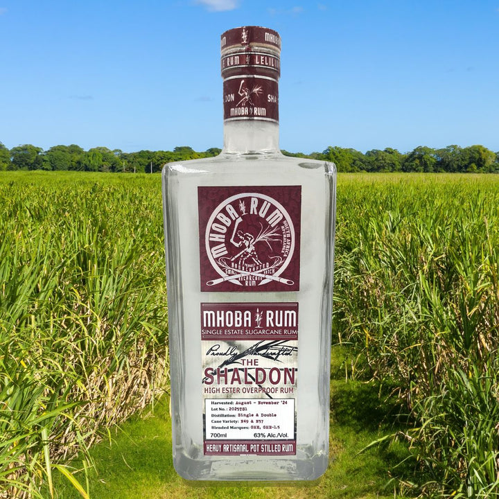 Mihoba Rum bottle in a field with trees in the background