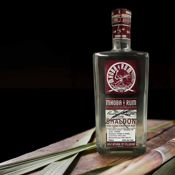 Bottle of Mhoba Rum on a wooden surface with a dark background