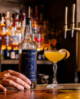 Bottle of Smith & Cross rum on a bar with a cocktail in the background