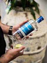 Person holding a bottle of Patron tequila with a glass of lime and ice.