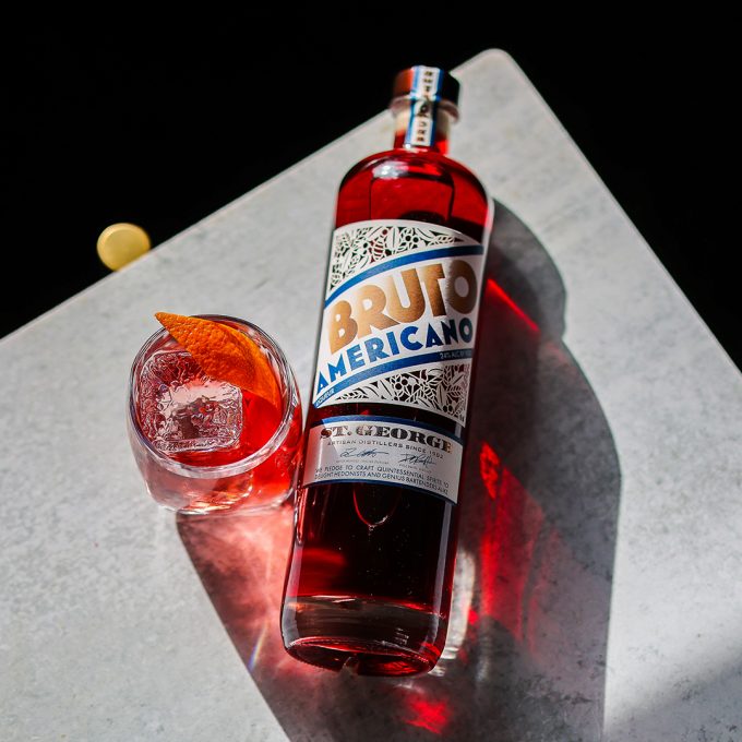 Bottle of St. George Bruto Americano with a cocktail on a dark surface