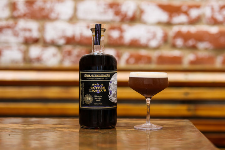 Bottle of coffee liqueur next to a cocktail glass with a blurred background