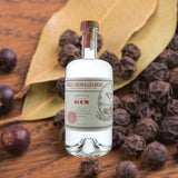 A bottle of St. George Dry Rye Gin against a backdrop of juniper berries, peppercorn, and sumac leaves.