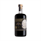 A dark rich liquid in a beautiful, apothecary shaped bottle. The label reads NOLA Coffee Liqueur. There's a sepia toned illustration of an old style Spanish buildings in an oval emblem on the bottle.