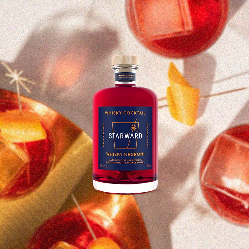 An image of Starward Whisky Negroni set against a backdrop of an overhead shot of negronis on a gold tray garnished with orange twists.