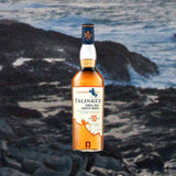 Bottle of Talisker 10 Year Old Single Malt Scotch Whisky over back drop of waves crashing up against rocks.