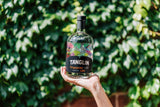 Person holding a bottle of Tanglin Singapore Gin against a green leafy background