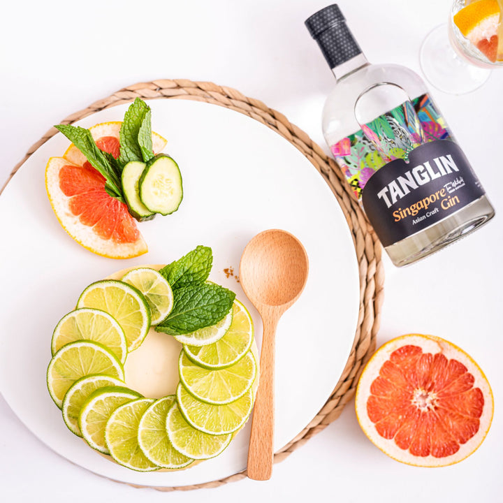 Bottle of Tanglin Singapore Dry Gin with citrus fruits on a white background