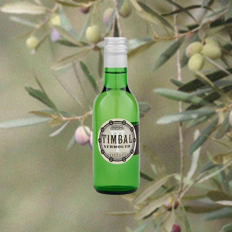 A shorter bottle - 500ml -in simple green. A plain label that reads: Catalan Aperitif. TIMBAL Vermouth Extra Dry on the front. All set against a lovely backdrop of orange and light purple olives growing on trees, evoking the briny flavor found in the vermouth.