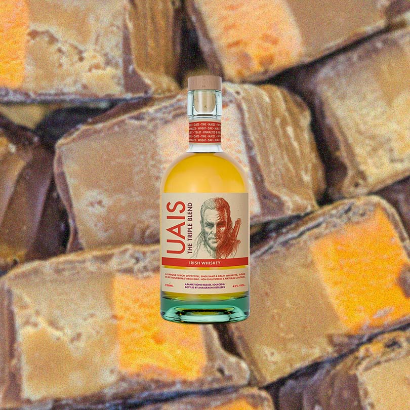 Bottle of UAIS The Triple Blend Irish Whiskey over back drop image of chocolates.