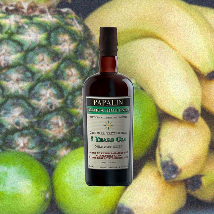 A bottle of Papalin Jamaica 5 Years Old High Ester Overproof Rum with a dark label and a clear bottle showing the amber-colored rum inside over a backdrop image of fruits.