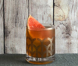 Cocktail in a decorative glass with a grapefruit wedge against a wooden background