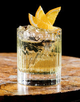 Glass of cocktail with lemon garnish on a wooden surface