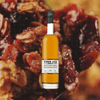 Bottle of Bottle of Widow Jane Paradigm Rye over backdrop image of candied nuts and raisins.