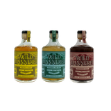 Three bottles of Wild Mannered liquor with different colored labels on a white background