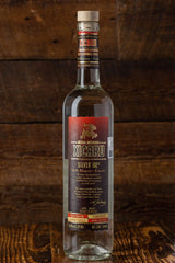 A bottle of Xicaru Silver 102 standing on its own, center stage on a wooden bar.