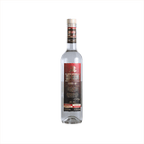 A tall artesanal shaped bottle with a red label and gold writing stating: Xicaru Mexcal Silver 102 Proof