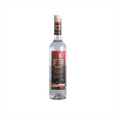 A tall artesanal shaped bottle with a red label and gold writing stating: Xicaru Mexcal Silver 102 Proof