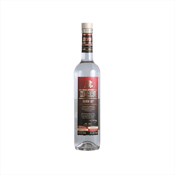 A tall artesanal shaped bottle with a red label and gold writing stating: Xicaru Mexcal Silver 102 Proof