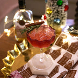 Red cocktail with garnish on a festive table with Christmas decorations.