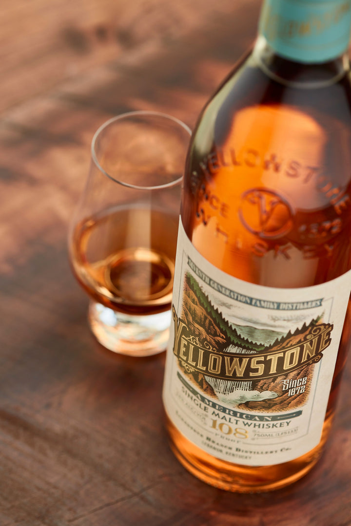 Yellowstone whiskey bottle and glass on a wooden surface