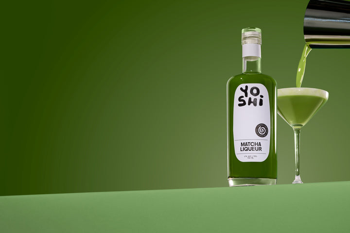 Bottle of Yoshi Matcha Liqueur with a glass being filled on a green background